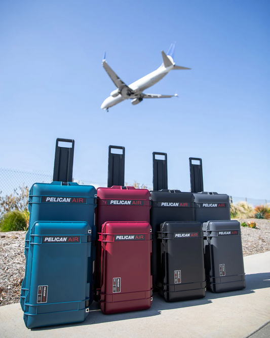Pelican Air travel cases with wheels lined up outdoors as an airplane flies overhead, showing durability and mobility