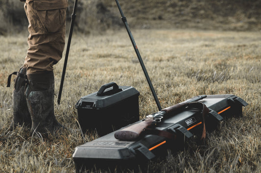 Professional camera setup in the wild showing a rugged photography hard case and a tactical gun case for outdoor protection.